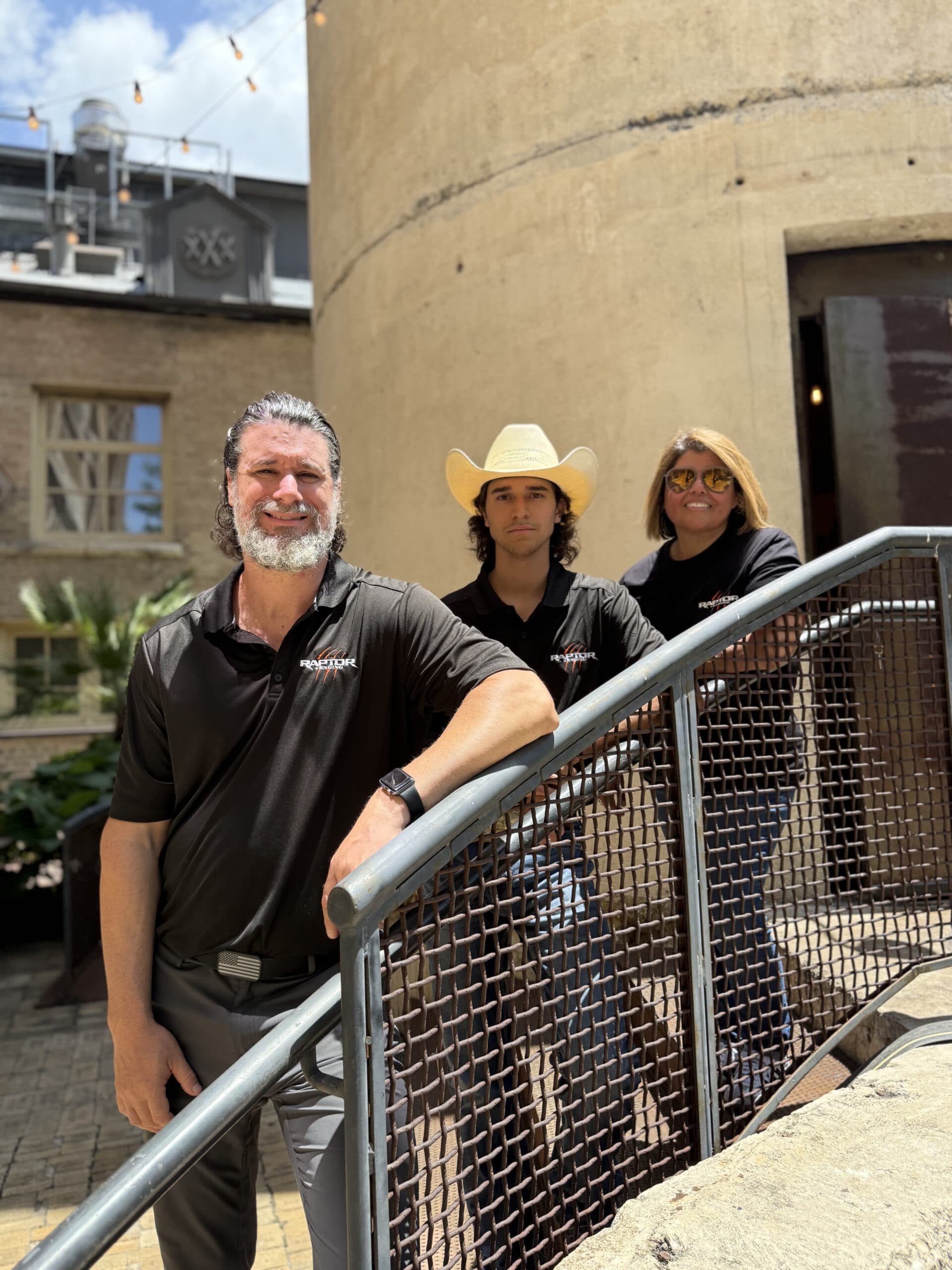The three Raptor Vending co-founders on an outdoor stairway, wearing Raptor Vending shirts